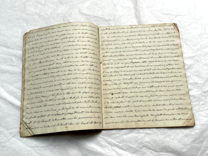 Late 19th Century handwritten French manuscript book with aged pages open to reveal flowing script.
