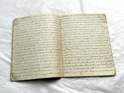 Late 19th Century handwritten French manuscript book with aged pages open to reveal flowing script.