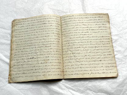 Late 19th Century handwritten French manuscript book with aged pages open to reveal flowing script.