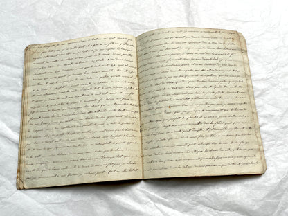 Late 19th Century handwritten French manuscript book with aged pages open to reveal flowing script.