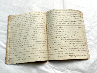 Late 19th Century handwritten French manuscript book with aged pages open to reveal flowing script.
