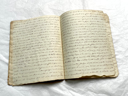 Late 19th Century handwritten French manuscript book with aged pages open to reveal flowing script.