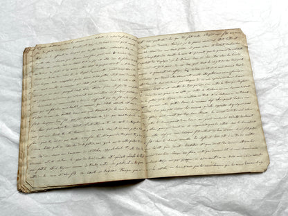 Late 19th Century handwritten French manuscript book with aged pages open to reveal flowing script.