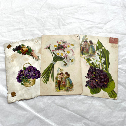 1900s lot of three antique French postcards featuring children, daisies, pansies, and lily of the valley.