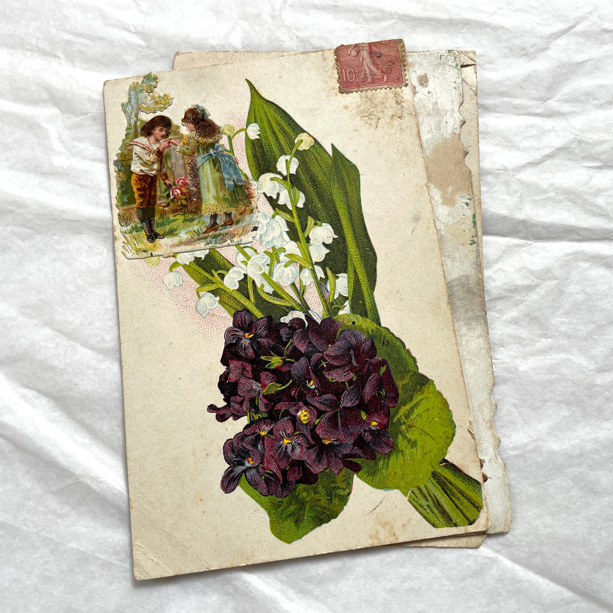 1900s lot of three antique French postcards featuring children, daisies, pansies, and lily of the valley.