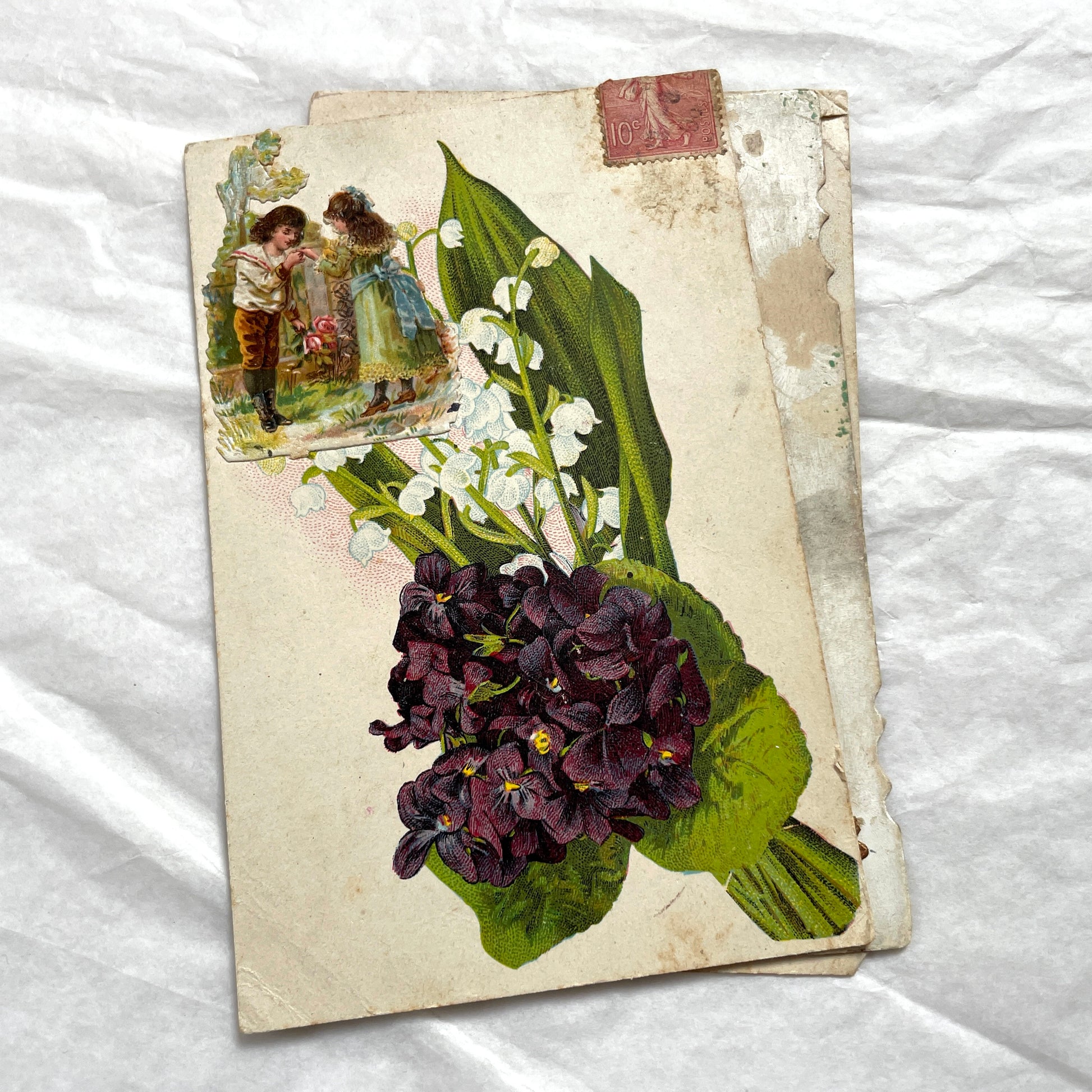 1900s lot of three antique French postcards featuring children, daisies, pansies, and lily of the valley.