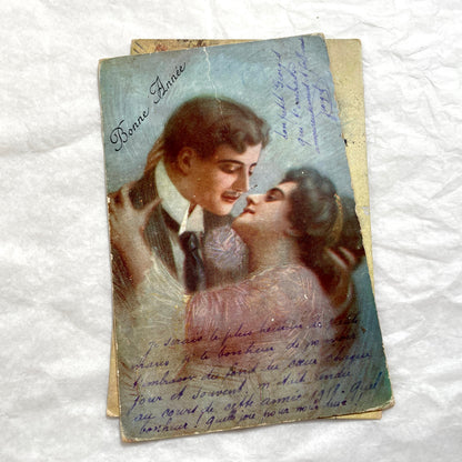 Two 1910s vintage French postcards featuring romantic couples with flowers and New Year greetings.