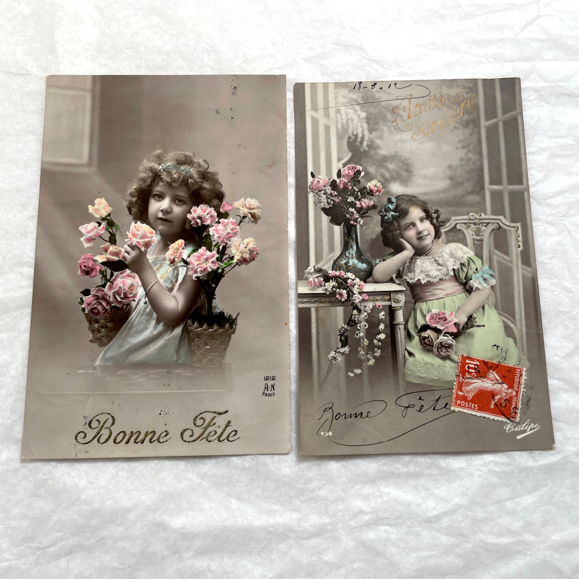 Two French postcards from the 1910s depicting young girls with flowers and 'Bonne Fete' greetings.