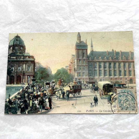 1900s French postcard depicting a bustling street scene in Paris with horse-drawn carriages and La Conciergerie.