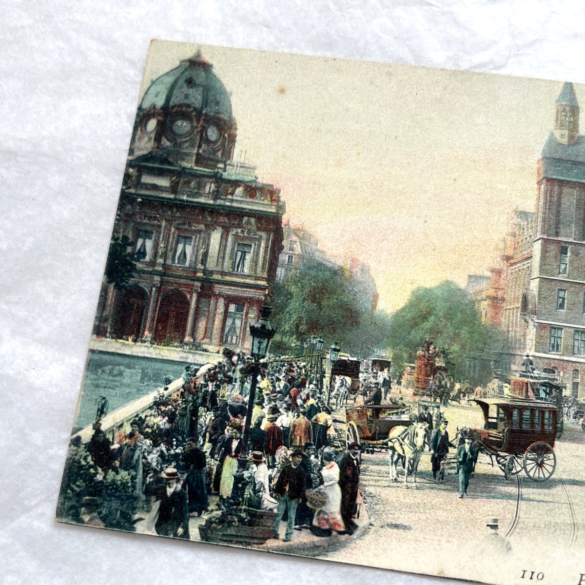 1900s French postcard depicting a bustling street scene in Paris with horse-drawn carriages and La Conciergerie.