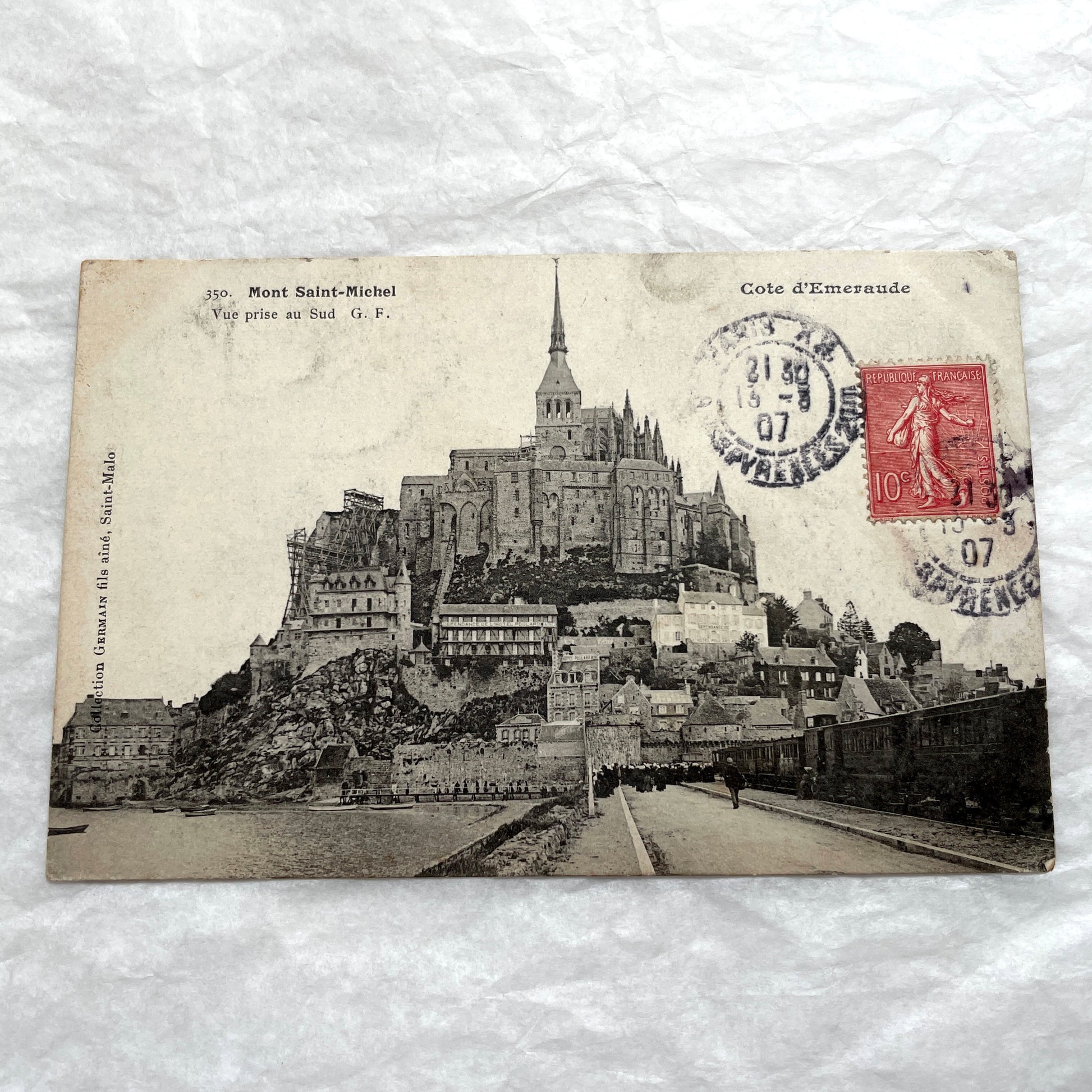 1900s postcard of Mont Saint-Michel abbey in France, showing its majestic medieval architecture and surrounding village.