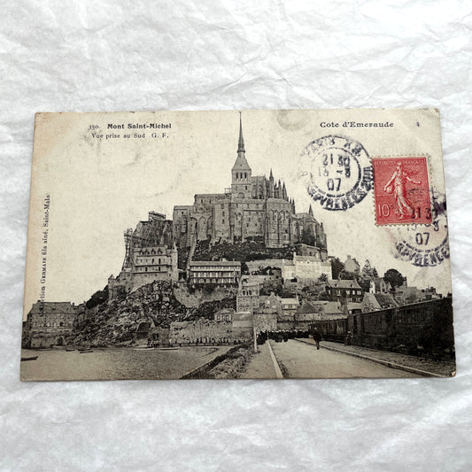 1900s postcard of Mont Saint-Michel abbey in France, showing its majestic medieval architecture and surrounding village.