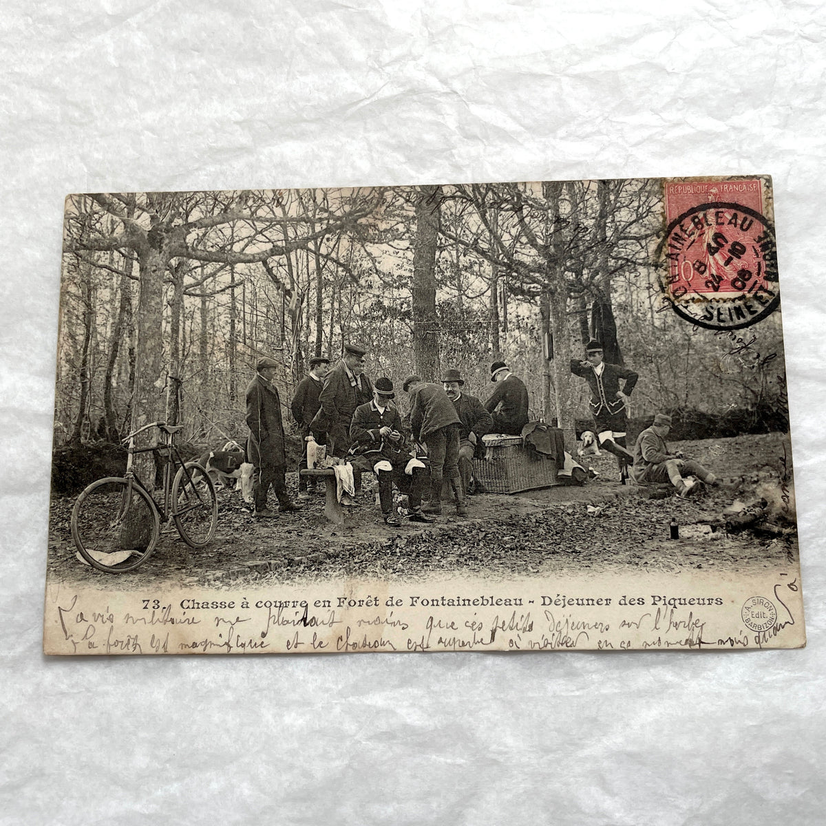1900s French postcard showing huntsmen and a vintage bicycle having a picnic in Fontainebleau Forest.