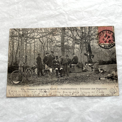 1900s French postcard showing huntsmen and a vintage bicycle having a picnic in Fontainebleau Forest.