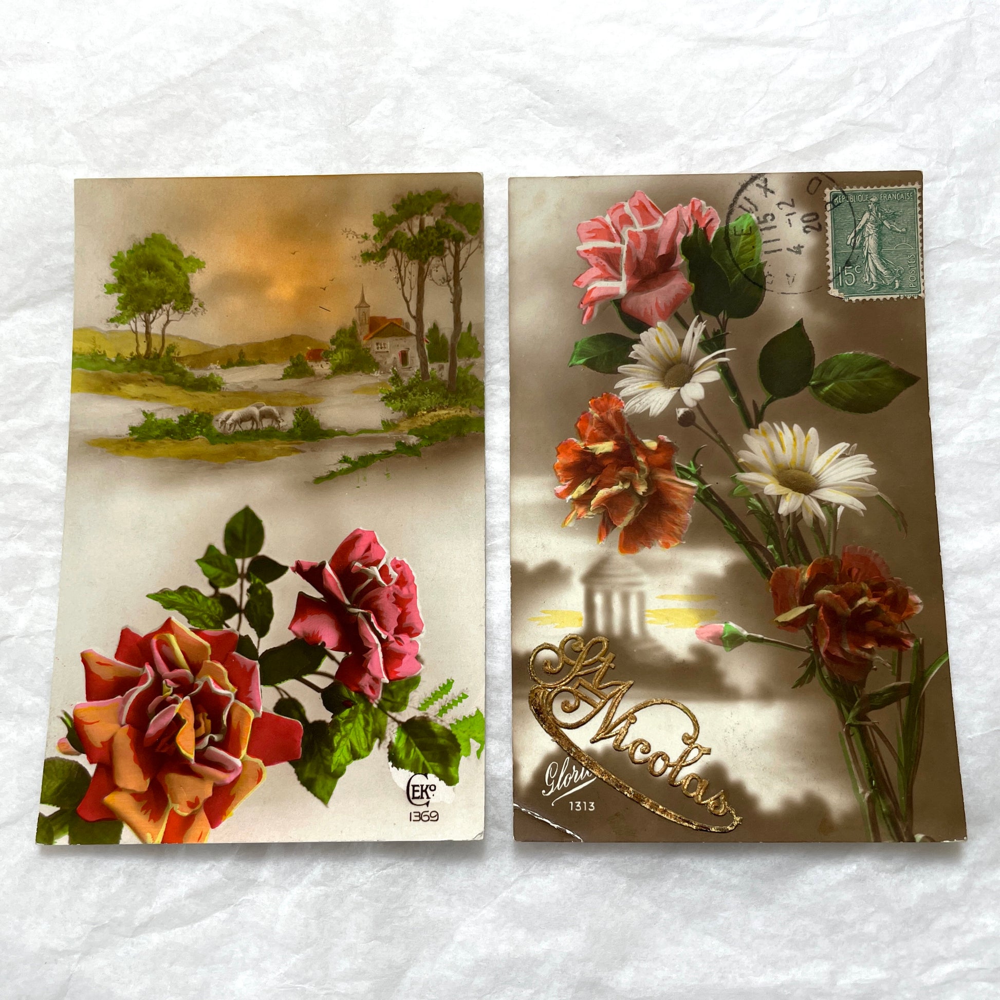 1910s French Postcard Lot featuring embossed floral designs with roses and daisies, and a peaceful village landscape.