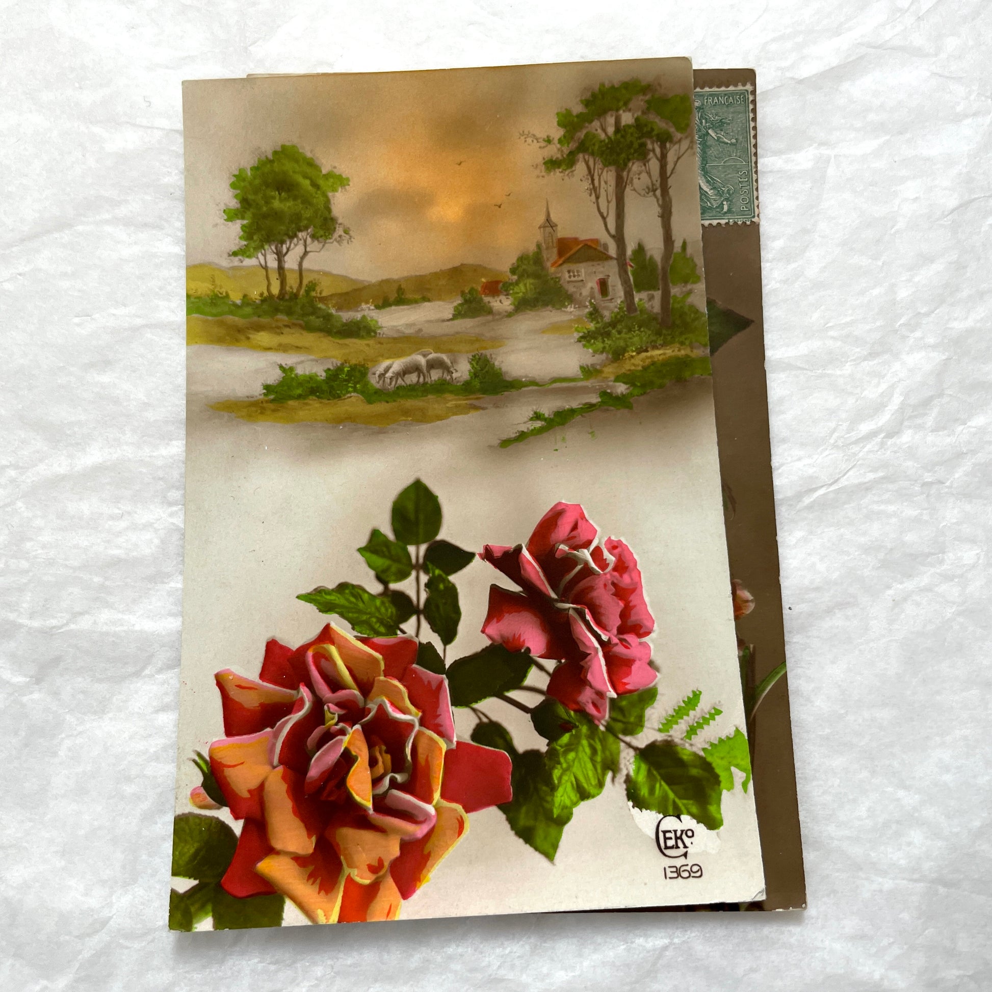 1910s French Postcard Lot featuring embossed floral designs with roses and daisies, and a peaceful village landscape.