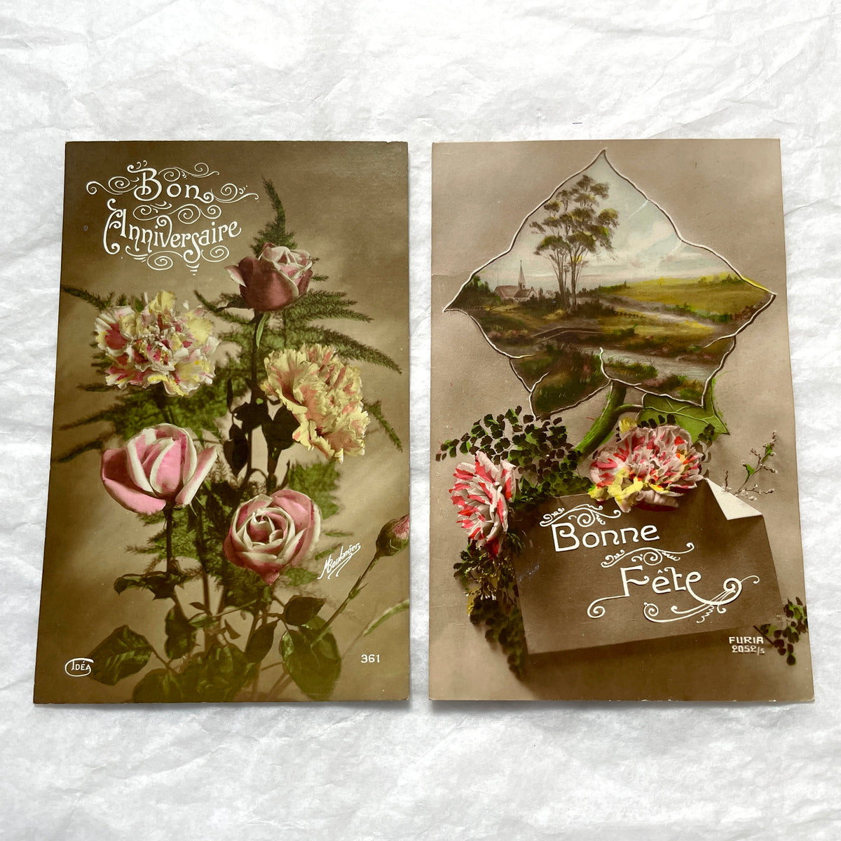 1910s French postcard lot with floral designs and a die-cut landscape scene of a village and church.